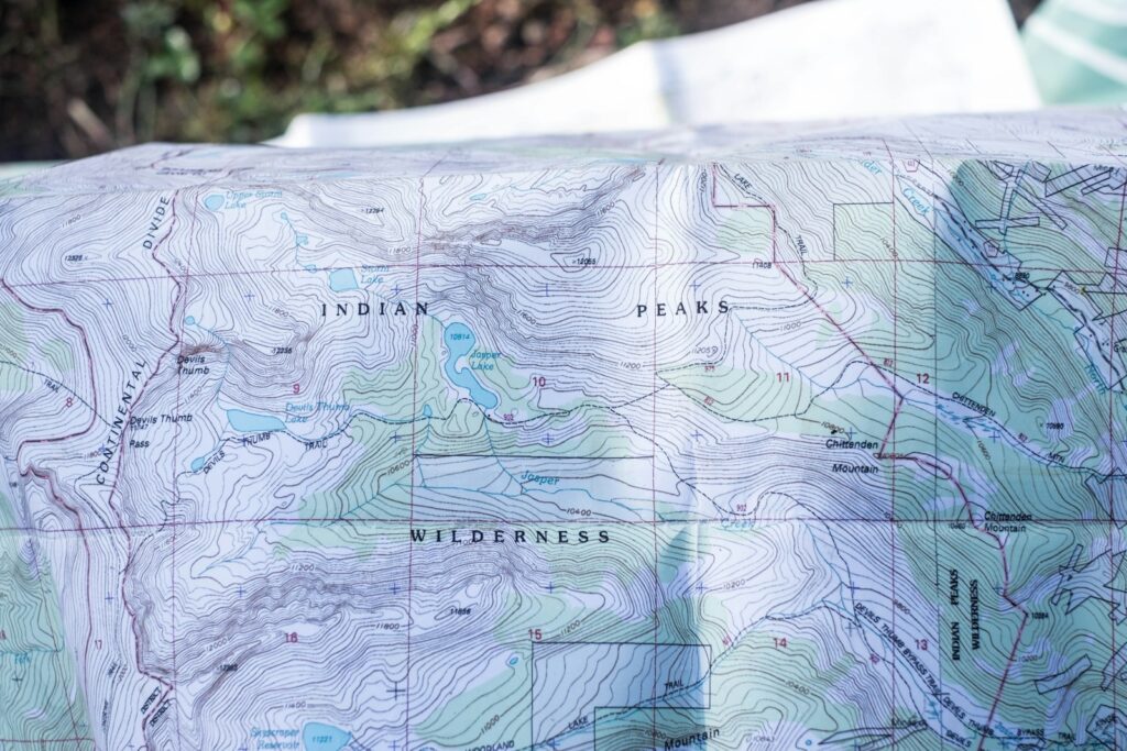 Hiker reading a topographic map and compass while planning a route across mountain terrain