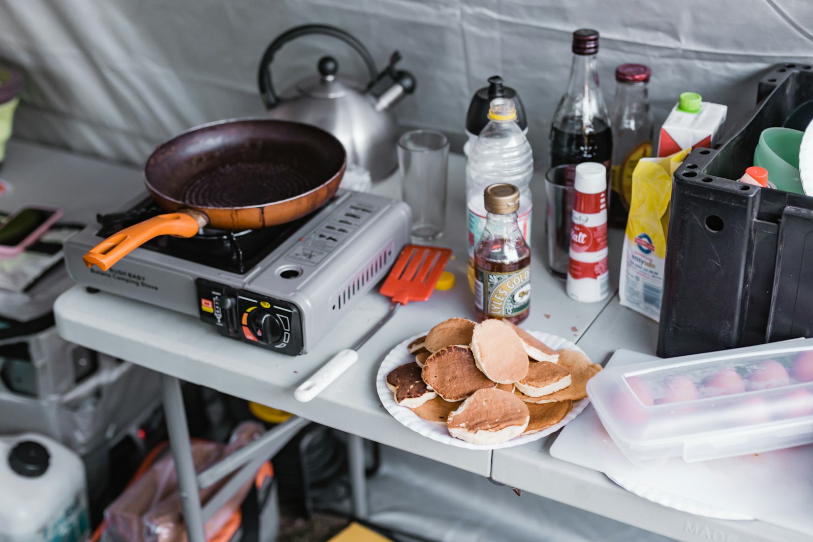 Camper preparing a meal on a portable stove at an organized outdoor cooking station
