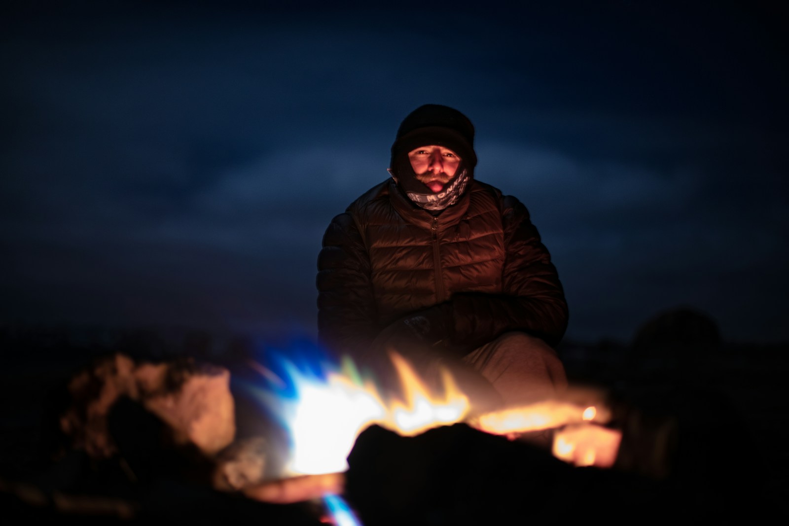 Winter camper beside a tent in snowy weather wearing warm layered clothing