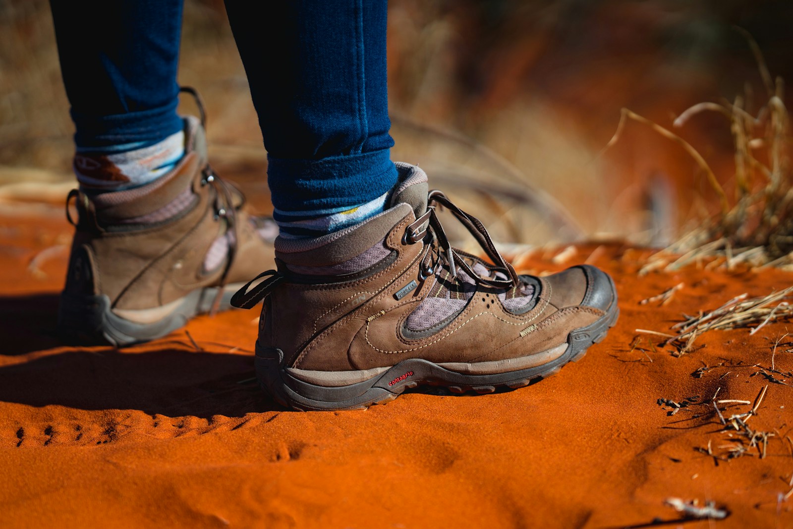Hiker wearing trail shoes on a rocky path, showing footwear suited to rough terrain