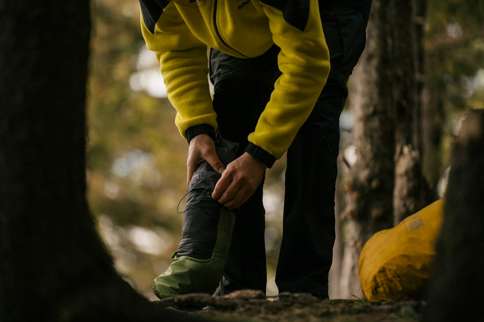 Hiker checking a sore heel and treating a foot blister beside a hiking trail