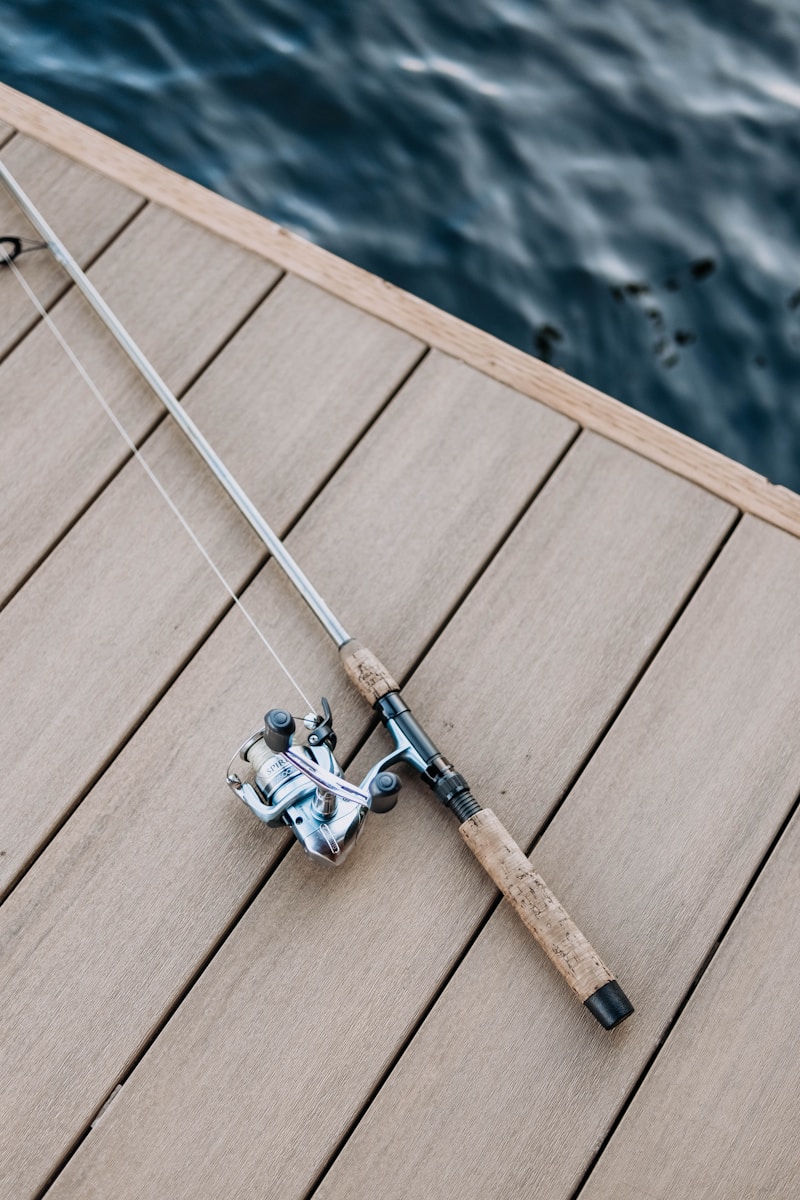 Angler holding a fishing rod beside the water while choosing tackle for a day of fishing