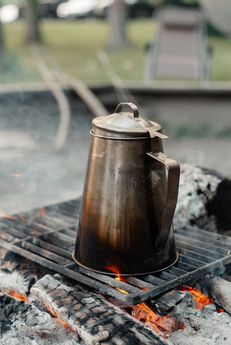 Camping coffee percolator brewing over a safe outdoor heat source at camp
