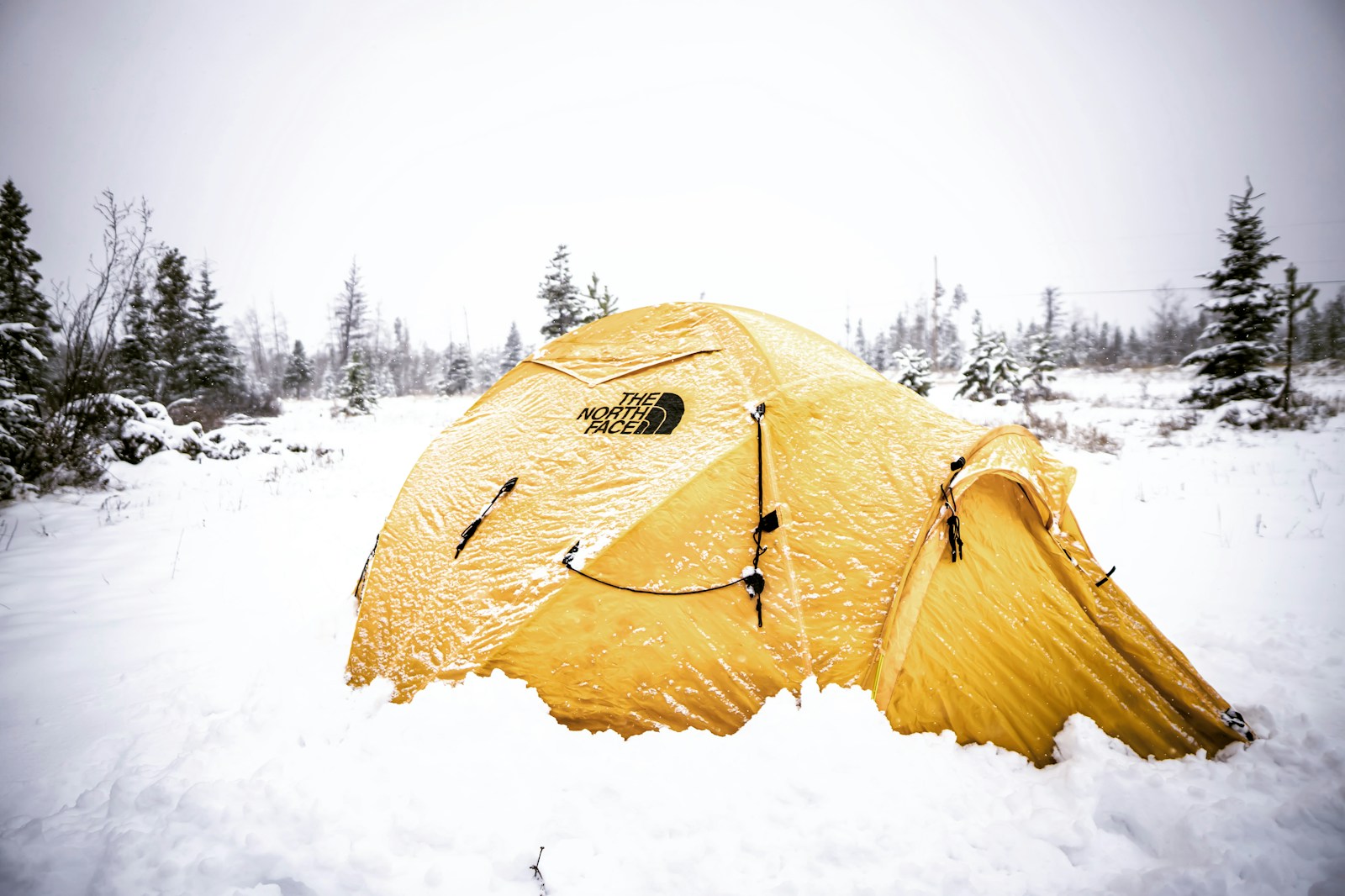 Four-season tent pitched on packed snow for a cold winter camping night