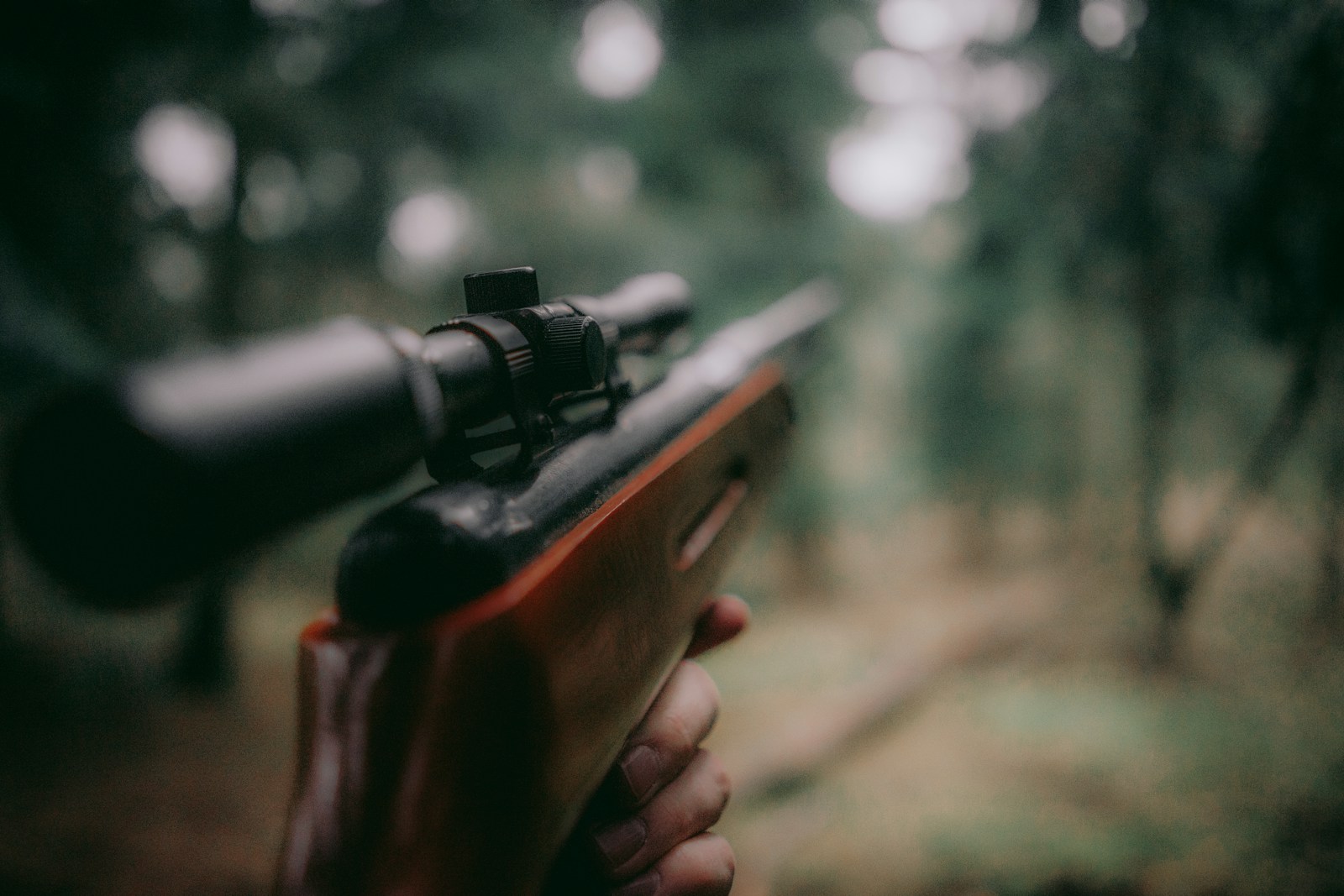 Deer hunter carrying a secured hunting rifle through wooded terrain during deer season