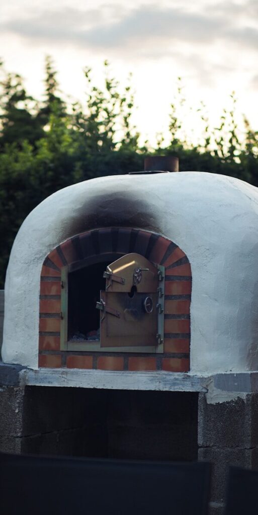 Brick wood-fired pizza oven built in a backyard outdoor cooking area