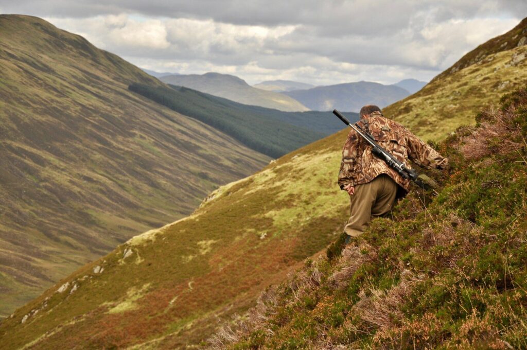 Hunter wearing layered technical hunting clothing in cold mountain terrain