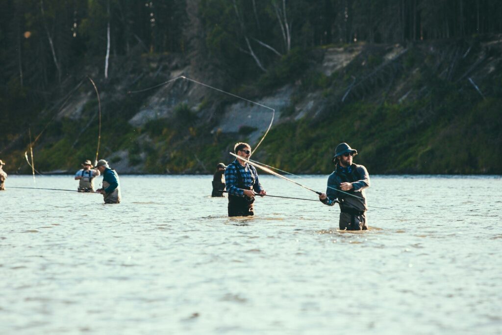 Angler fishing an Alaska salmon river in summer with forested mountains in the background