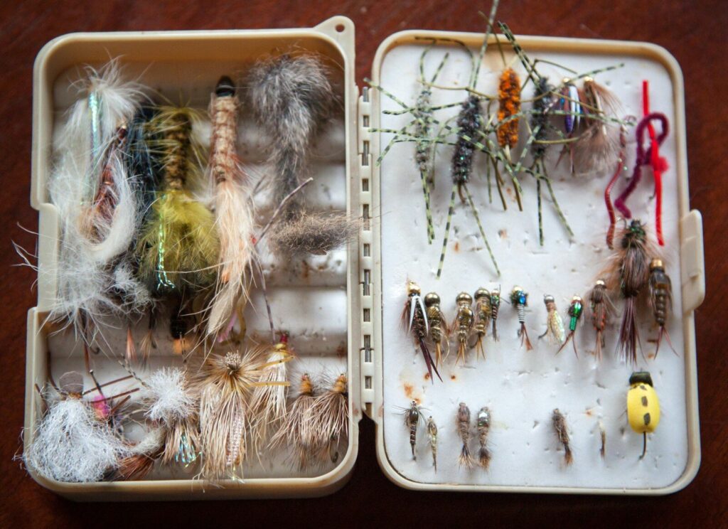 Beginner tying a Woolly Bugger fishing fly at a vise with thread, marabou, and hackle