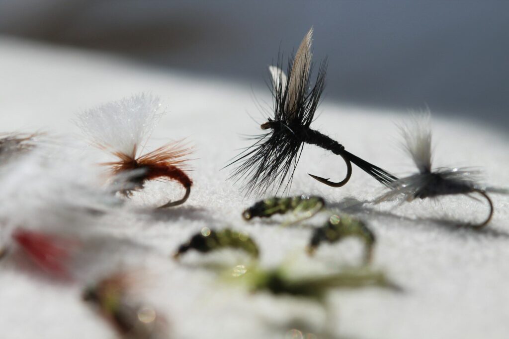 Fly tier working at a vise with thread and materials to make a beginner fishing fly