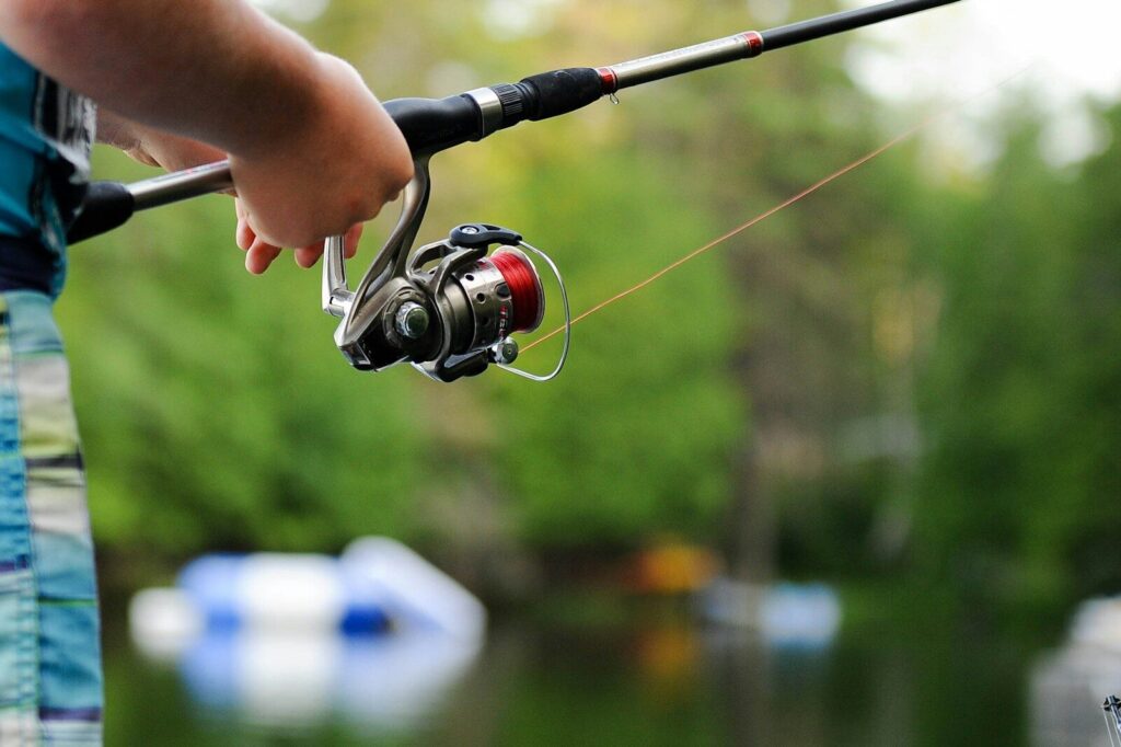 Bass fishing rod and reel spooled with line beside lures for fishing around grass and cover