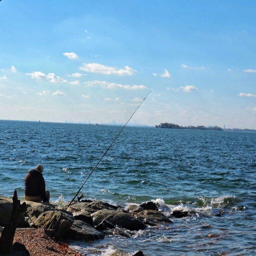 Angler fishing Connecticut waters during a summer morning with Long Island Sound in the distance